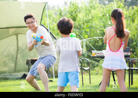 Glücklicher Vater und die Kinder spielen Spritzpistolen Stockfoto