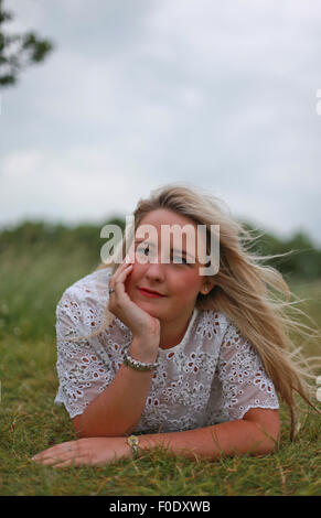 Ziemlich junges Mädchen mit langen blonden Haaren in einem Feld liegen Stockfoto