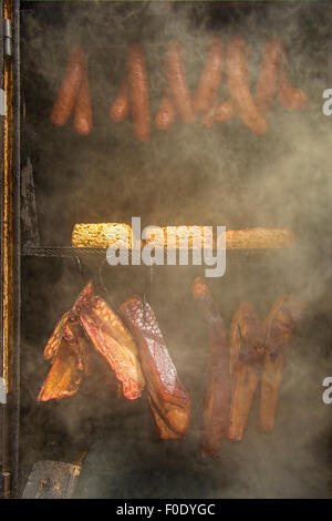 Mais, hausgemachte Wurst, Käse und Schinken im Barbecue-Smoker. Stockfoto