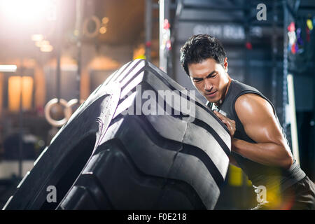 Junger Mann drängen große Reifen in Crossfit gym Stockfoto