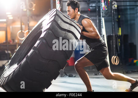 Junger Mann drängen große Reifen in Crossfit gym Stockfoto