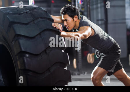 Junger Mann drängen große Reifen in Crossfit gym Stockfoto