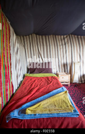 Handtücher auf einem kleinen Bett in einem traditionellen farbigen Berberzelt in Marokko. Stockfoto