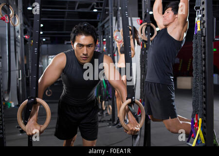 Junge Sportler mit Gymnastik Ringen im Fitness-Studio trainieren Stockfoto