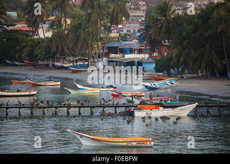 Bunte hölzerne Fischerboote in der Bucht von Pampatar mit Lasten von Pelikan auf dem hölzernen Pier verankert. Insel Margarita. Stockfoto