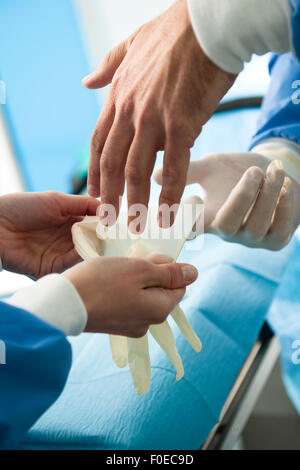 Nahaufnahme eines männlichen Chirurgen Schutzhandschuhe tragen Stockfoto