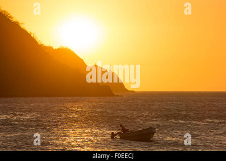 Silhouetten von Fischer arbeiten auf einem kleinen Boot in Taganga während einer klaren orange Sunset Bay verankert. Kolumbien-2014. Stockfoto