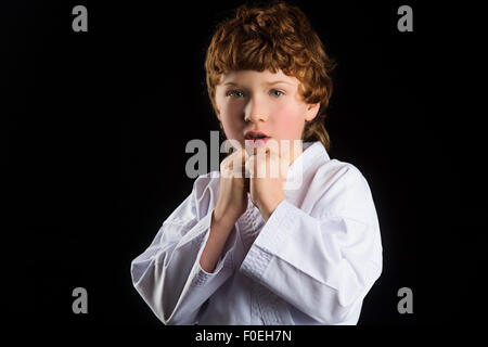 Karate-junge im weißen Kimono auf schwarzem Hintergrund isoliert Stockfoto