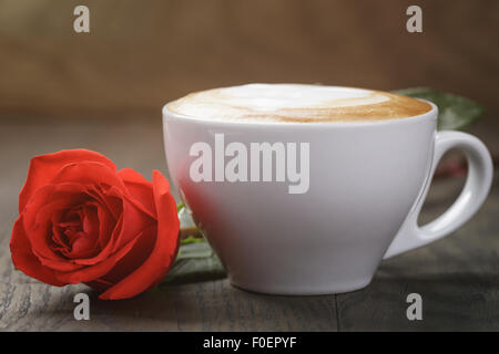 frischen Cappuccino mit roten Rose auf Holztisch Stockfoto