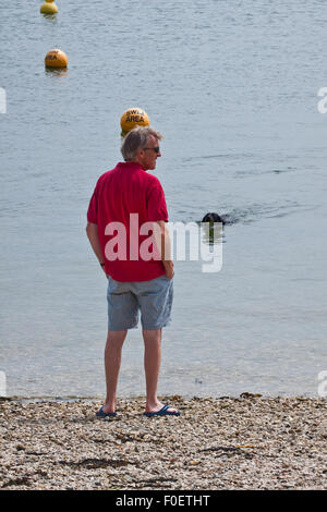 Einfache Freuden - ein Mann und sein Hund am Meer an einem Cornish Strand genießen Stockfoto