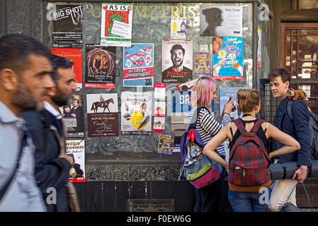 Edinburgh Fringe Festival - eine junge Frau nimmt ein Foto während Fußgänger Filer auf einem leeren Schaufenster geklebt vorbeigehen. Stockfoto