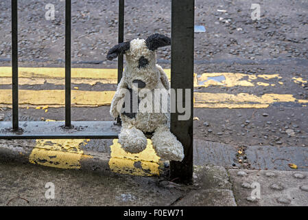 Ein Kind verloren Kuscheltier Hundesitting am Geländer, die darauf warten, gefunden werden. Stockfoto