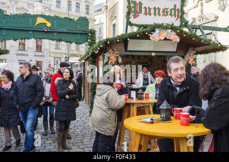 Menschen Sie trinken Punsch auf einem Weihnachtsmarkt in Freyung Quadrat. Wien, Österreich Stockfoto