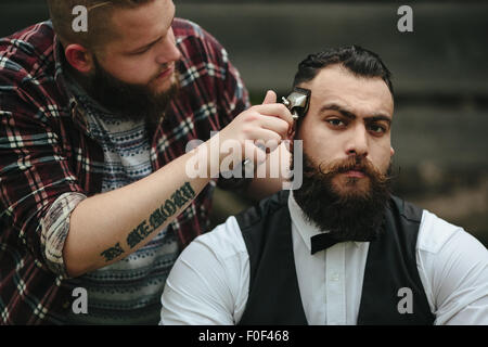 Barbier rasiert ein bärtigen Mannes Stockfoto