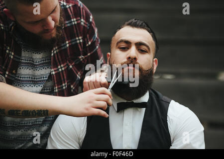 Barbier rasiert ein bärtigen Mannes Stockfoto