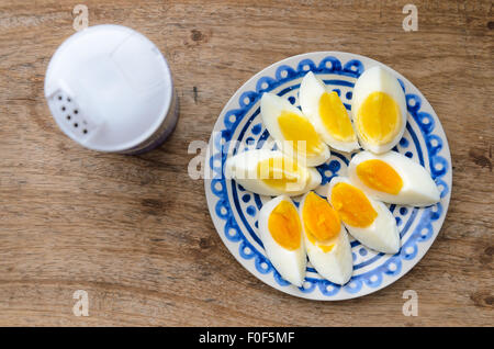 Zwei Farben Eigelb geschnittenen harte gekochte Eiern in einer blauen dekorierten Platte auf Holz Küchentisch. Stockfoto