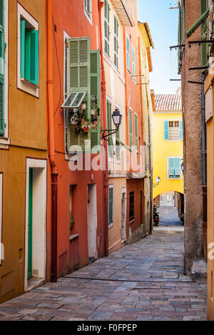 Reihe von bunten Altbauten mit hellen Fenster Fensterläden entlang der Straße mit Kopfsteinpflaster in der mittelalterlichen Stadt Villefranche-Sur-Mer am Fre Stockfoto