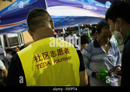 China. 14. August 2015. Eine ehrenamtliche verteilen Lebensmittel liefert für die Anwohner. -Eine gewaltige Explosion verursacht mindestens 55 Tote und 750 verletzt bei einer Lagerung von Chemikalien-Anlage in der chinesischen Stadt Tianjin in den frühen Morgenstunden des 13. August. Bildnachweis: Geovien So/Pacific Press/Alamy Live-Nachrichten Stockfoto