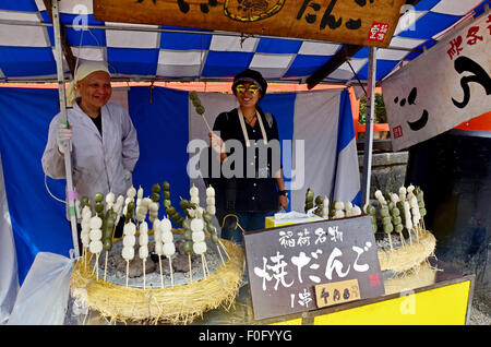 Thai-Frauen fotografieren mit Vender Dango japanische snack am Straßenevent Fushimi Inari-Taisha-Schrein von Inari, Fushimi Ku Stockfoto