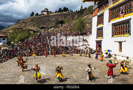 Tänzerinnen mit Zuschauern und Tempel im Hintergrund religiöses Fest Paro Bhutan Stockfoto