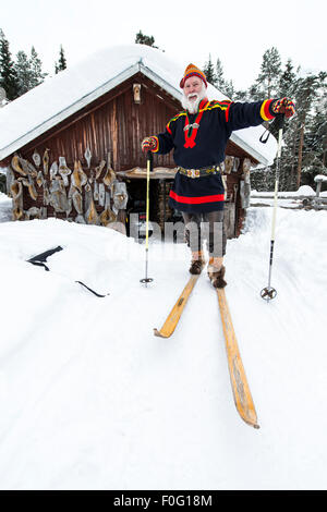 Sami Männchen auf Skiern mit Sami Haus im Hintergrund schwedischen Lappland Schweden Skandinavien Stockfoto