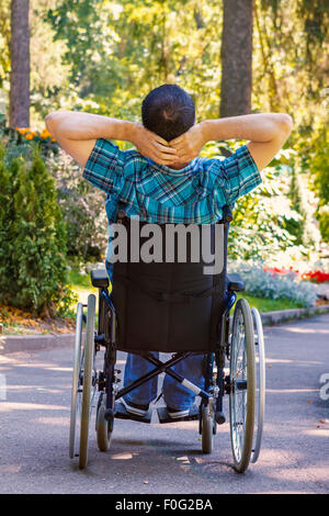 junger Mann im Rollstuhl an der frischen Luft im Stadtpark Stockfoto