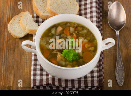 Schüssel mit Suppe mit Linsen, Bohnen, Huhn und Gemüse auf rustikalen Holztisch. Ansicht von oben Stockfoto