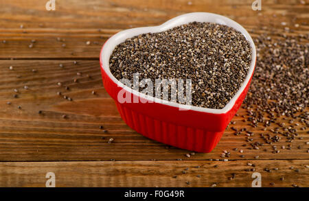 Chia-Samen in Herzförmige Schüssel auf rustikalen Holztisch. Selektiven Fokus Stockfoto