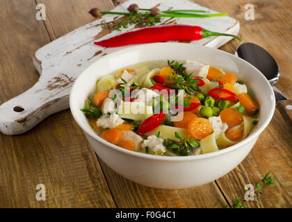 Huhn Suppe mit Gemüse und Nudeln auf Holztisch Stockfoto