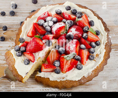 Kuchen mit frischen Beeren auf weißem Hintergrund aus Holz. Stockfoto