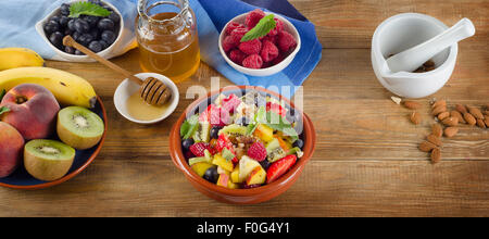 Gesunden selbstgemachten Obstsalat, frische Beeren und Früchte auf einem Holztisch. Ansicht von oben Stockfoto