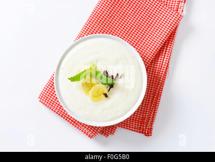 Schüssel mit glatten Milchbrei mit in Scheiben geschnittenen Bananen und geriebener Schokolade Stockfoto