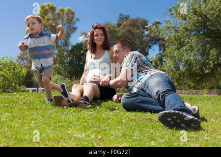 Glückliche Eltern, Kind und sonnigen Tag mit ihrem aktiven Sohn im Park während der sonnigen Sommertag zu genießen. Stockfoto