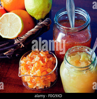 Frühstückstisch, frische Zitrusfrüchte, geöffnete Gläser von Konfitüren und Marmeladen, Schale mit kandierten Orangenschalen Stockfoto