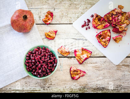 Granatapfel-Frucht, Schale und Samen auf einem rustikalen Tisch Stockfoto