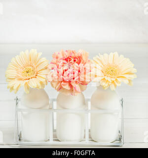 Gerbera und Nelken in drei Milchflaschen angeordnet Stockfoto