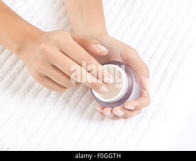 Frauenhand hält eine pflegende Creme für Gesichtspflege Stockfoto