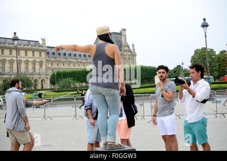 Eine junge Dame steht auf einem Podest vor dem Louvre in Paris, für ein Foto zu posieren. Stockfoto