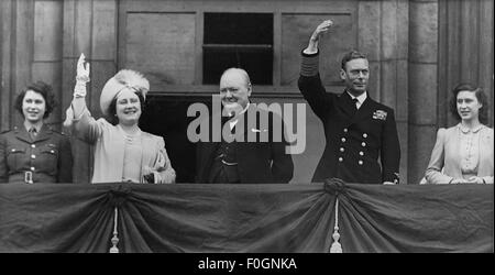 Sir Winston Churchill und die königliche Familie winken am VE Day 1945 im Buckingham Palace vor Menschenmengen. Von links: Prinzessin Elizabeth mit Königin Mutter, Winston Churchill, König George VI und Prinzessin Margaret Stockfoto