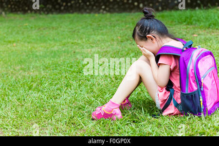 Stress Mädchen sitzen und denken auf dem Rasen Stockfoto