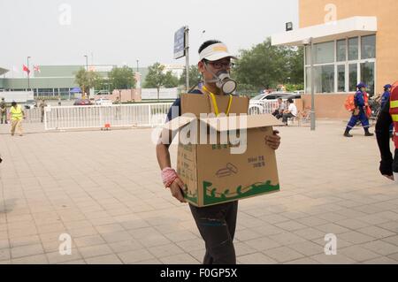 China. 15. August 2015. Ein freiwilliger mit Gasmaske, sich aus dem giftigen Gas gesehen im temporären Flüchtlingslager zu schützen. Die Zahl der Todesopfer steigt auf 104. Gemeinde beginnt zu evakuieren Anwohner aus dem temporären Lager befindet sich an einer lokalen Schule in der Nähe der Explosionszone, wie sie reichen die Sperrzone, 3 km von wo die Explosion geschah wie poison Luft, die Krebs verursachen könnte erkannt wird. © Geovien also/Pacific Press/Alamy Live-Nachrichten Stockfoto