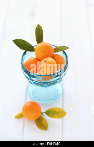 Vollreife haben, Kumquat, Citrofortunella Microcarpa in eine Glasschüssel auf Holzbrett Stockfoto