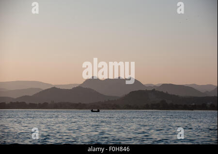 Udaipur, Rajasthan, Indien. Zwei Männer in einem Boot auf dem Pichola-See bei Sonnenuntergang. Stockfoto