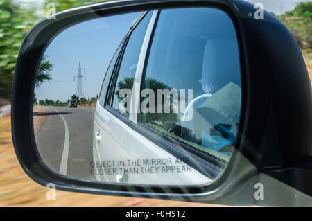 Blick durch den Rückspiegel eines Autos bewegen auf der Autobahn durch Wüste in hoher Geschwindigkeit mit den umliegenden Bewegung verwischt Textfreiraum Stockfoto