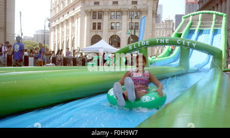 New York, USA. 15. August 2015. Besucher auf dem Festival "Summer Streets" gleiten Sie über eine 300 m lange Wasserrutsche in New York, USA, 15. August 2015. Foto: CHRISTINA HORSTEN/DPA/Alamy Live-Nachrichten Stockfoto