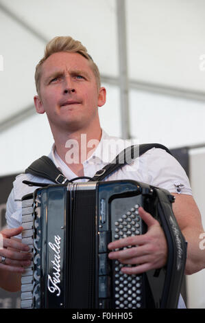 Crieff, Schottland, 16. August 2015. Die beliebte Folkband Skerryvore aus die Insel Tiree durchgeführt in Crieff Highland Games.das Band mischt verschiedene Musikstile um eine einmalige Leistung zu erstellen, die das Publikum genossen. Daniel Anthony Gillespie von Tiree auf der Ziehharmonika. Bildnachweis: Andrew Steven Graham/Alamy Live-Nachrichten Stockfoto