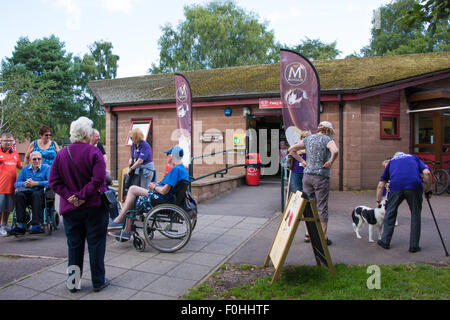 Zwei Männer in Rollstühlen und Menschen vor dem Eingang zum Cafe in Cannock Chase Visitor Centre UK Stockfoto