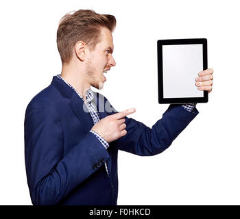 Studioaufnahme von ein zorniger junger Mann zeigt auf einem digitalen Tablet. Stockfoto