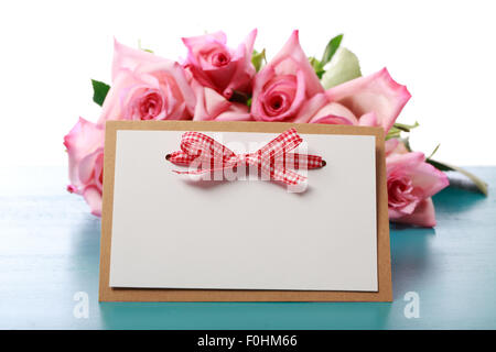 Handgemachte Textkarte mit rosa Rosen auf leichte blaue farbige Holzbrett Stockfoto