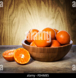 Mandarinen in Holzschale über Holzwand Hintergrund Stockfoto